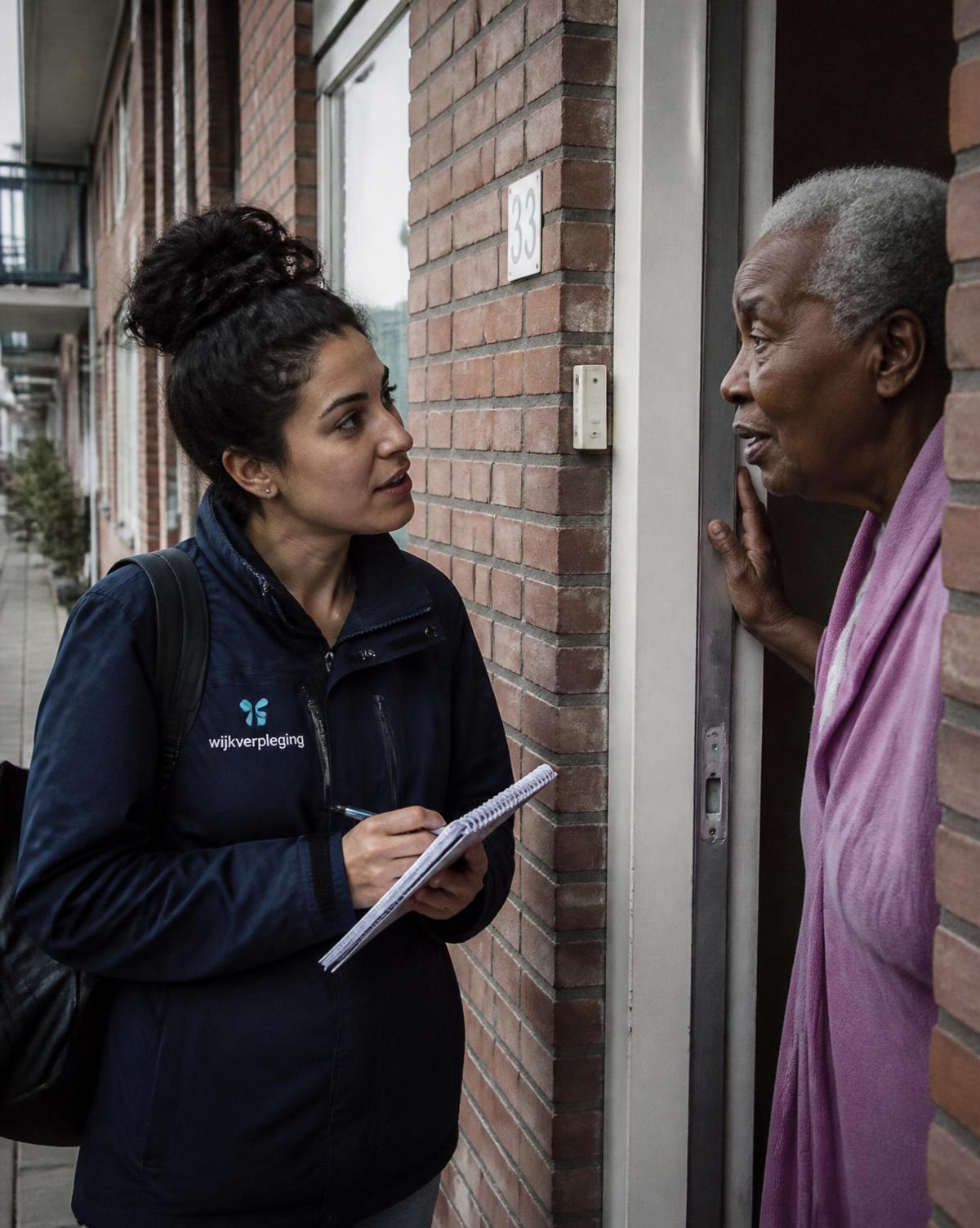 Wijkverpleegkundige in gesprek met een bewoner aan de deur